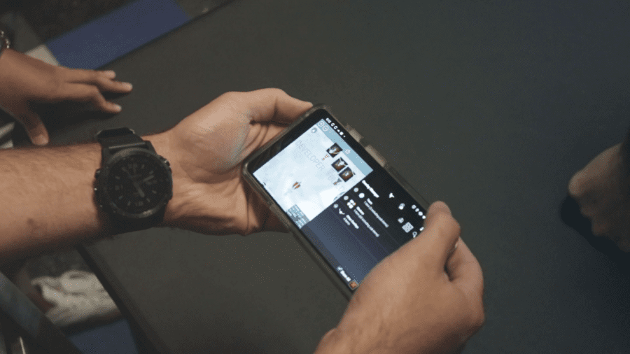 Person holding a smartphone horizontally, watching a video on YouTube. The screen displays video details and a portion of the playback interface.