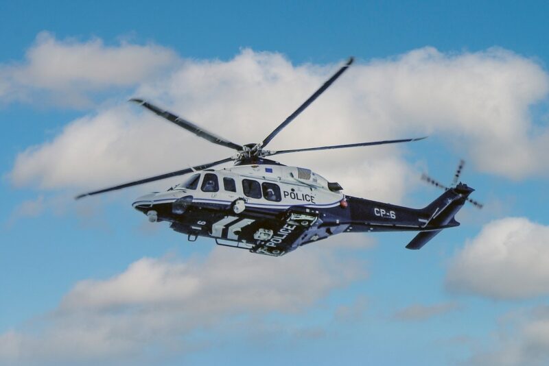 Police helicopter in flight against a blue sky with clouds.