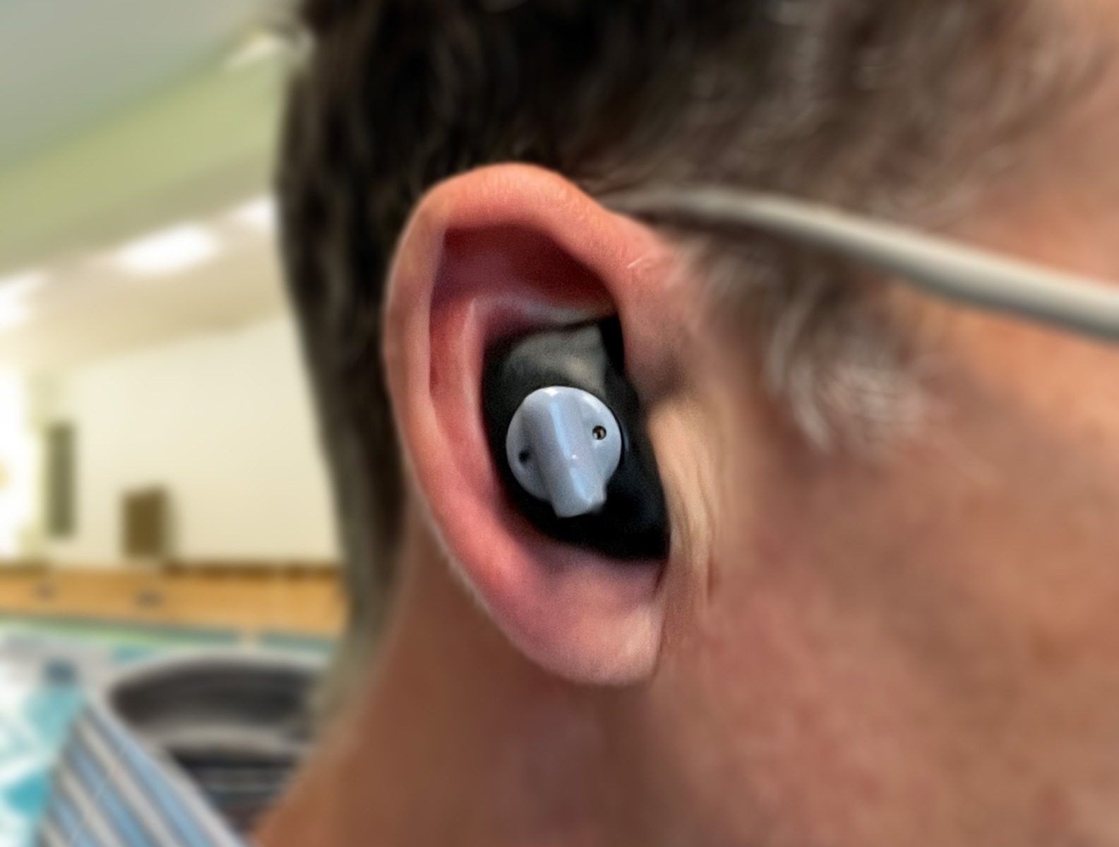 Close-up of a person's ear wearing a dolphin-shaped earplug.