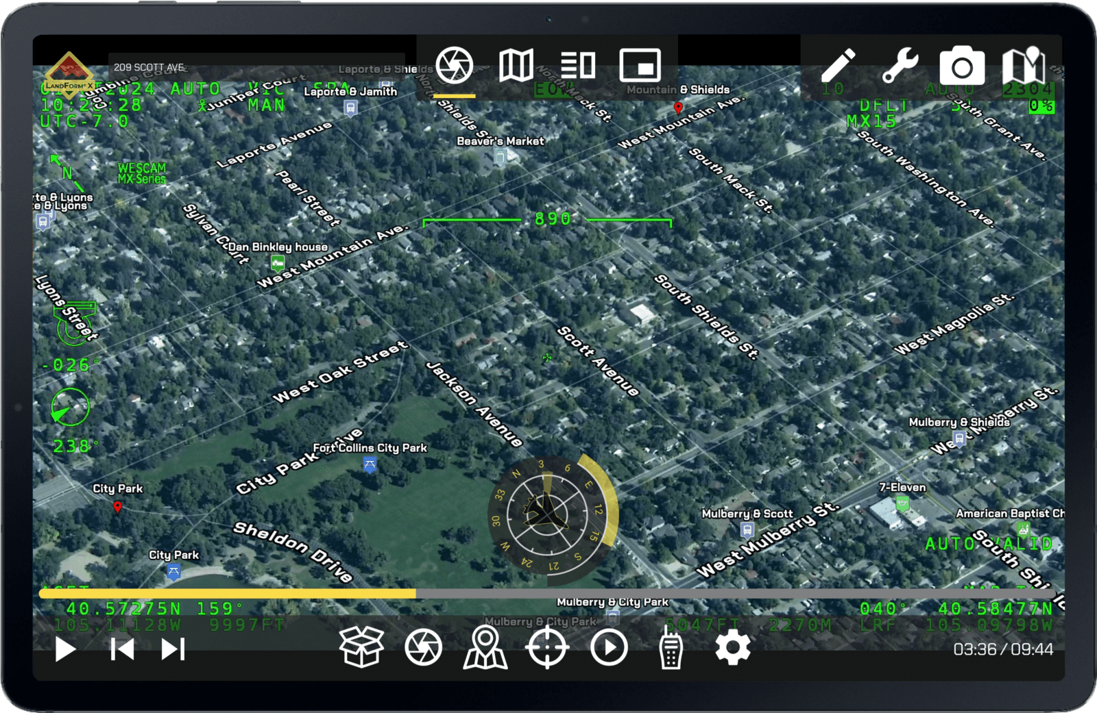 Aerial view of a suburban neighborhood displayed on a monitoring screen with advanced navigation and data overlay, showing streets, parks, and various control icons.