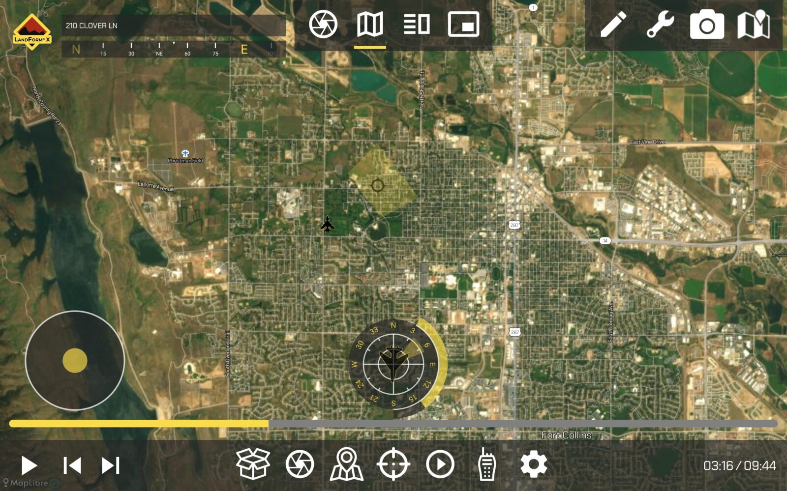 Aerial view of a city displayed on a digital interface with various icons and controls, including a compass and map tools, at the bottom of the screen.