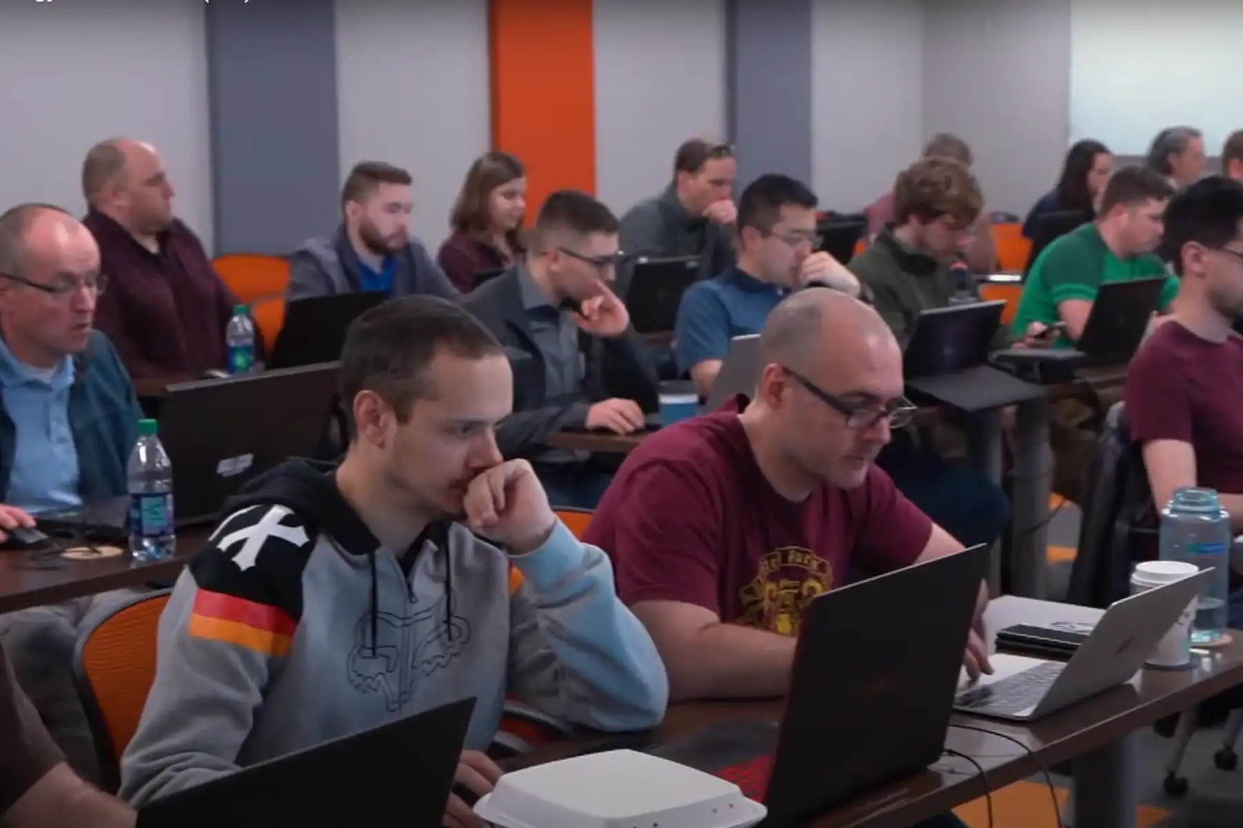 People sitting in a classroom at desks with laptops, focused on their screens.
