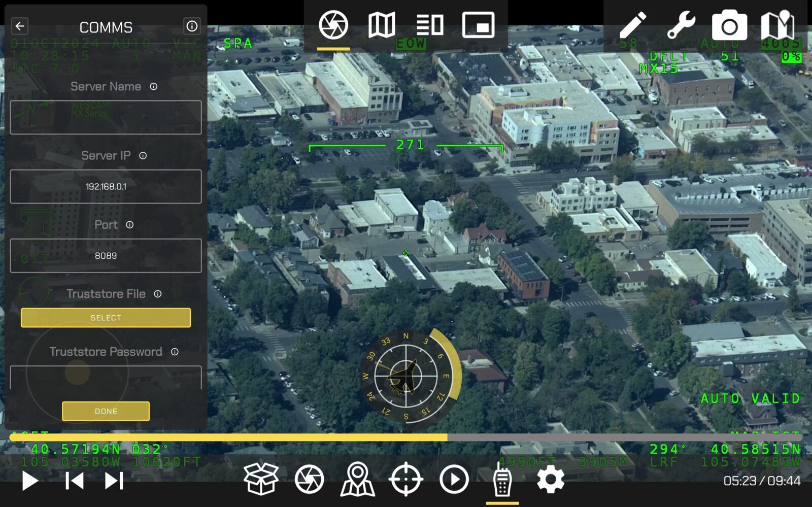 Aerial view of an urban area with a digital overlay featuring a compass, grid coordinates, and communication settings on the left side of the image.